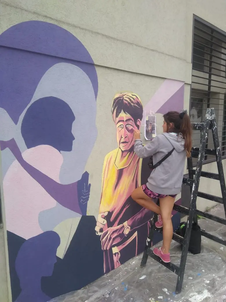 Juli pintando el mural de ATE desde una escalera